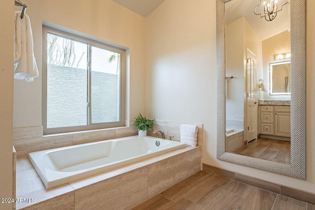 bathroom featuring vanity, tiled bath, and a chandelier