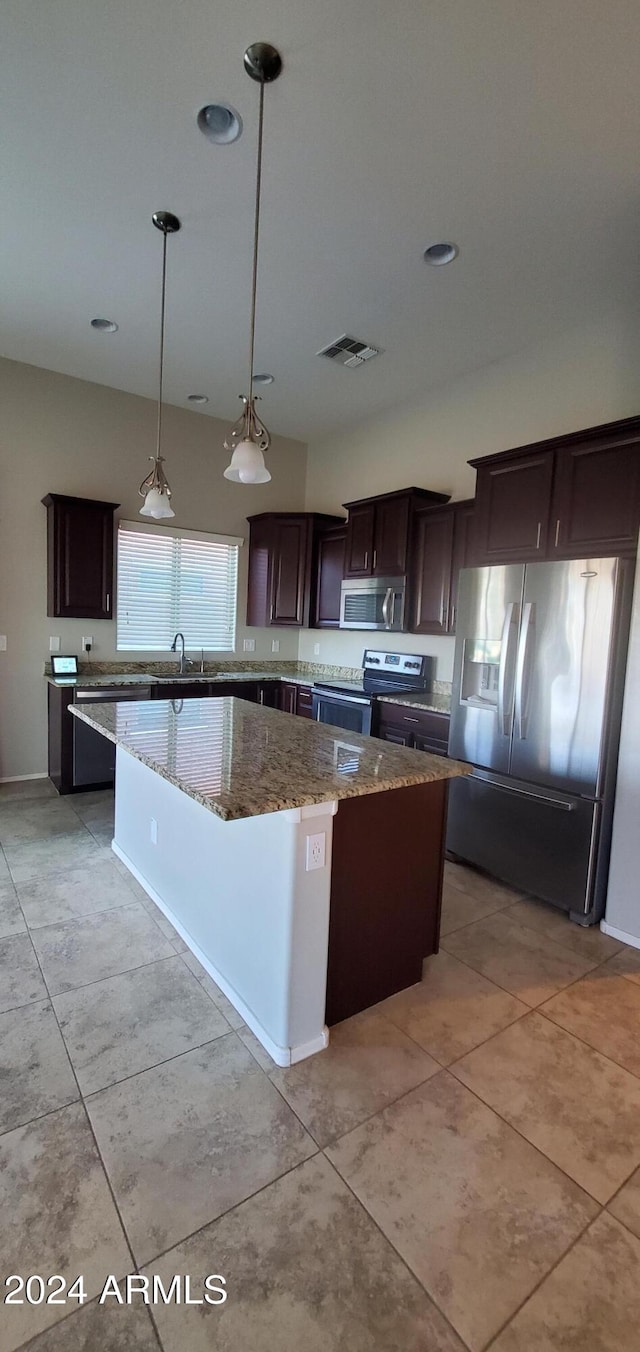 kitchen featuring a kitchen island, appliances with stainless steel finishes, light stone counters, and decorative light fixtures