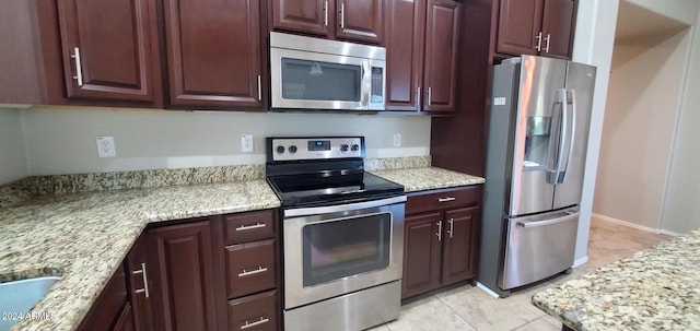 kitchen featuring appliances with stainless steel finishes, light tile patterned floors, and light stone counters