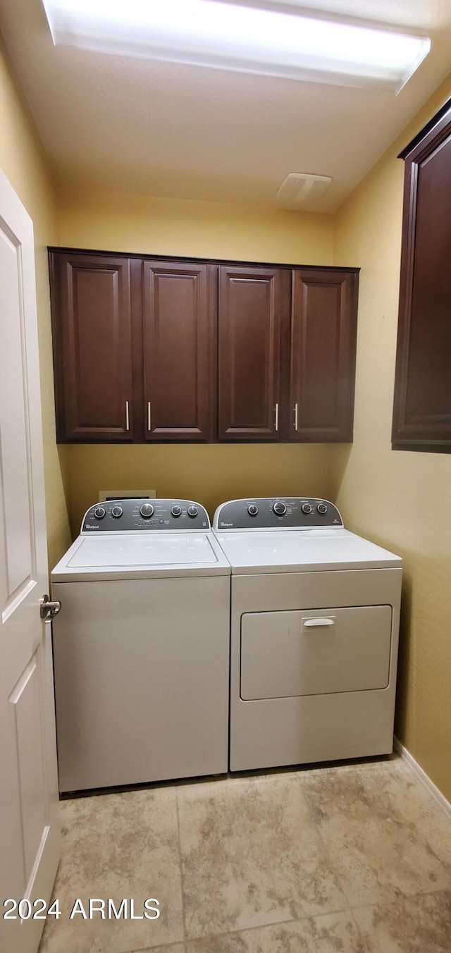 clothes washing area with cabinets and separate washer and dryer