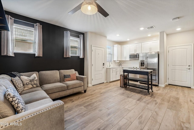 living room with ceiling fan, light hardwood / wood-style flooring, and sink