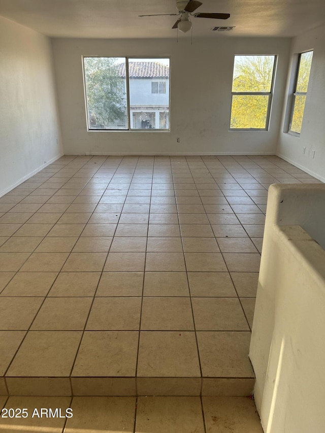 unfurnished room with plenty of natural light, a ceiling fan, light tile patterned floors, and visible vents