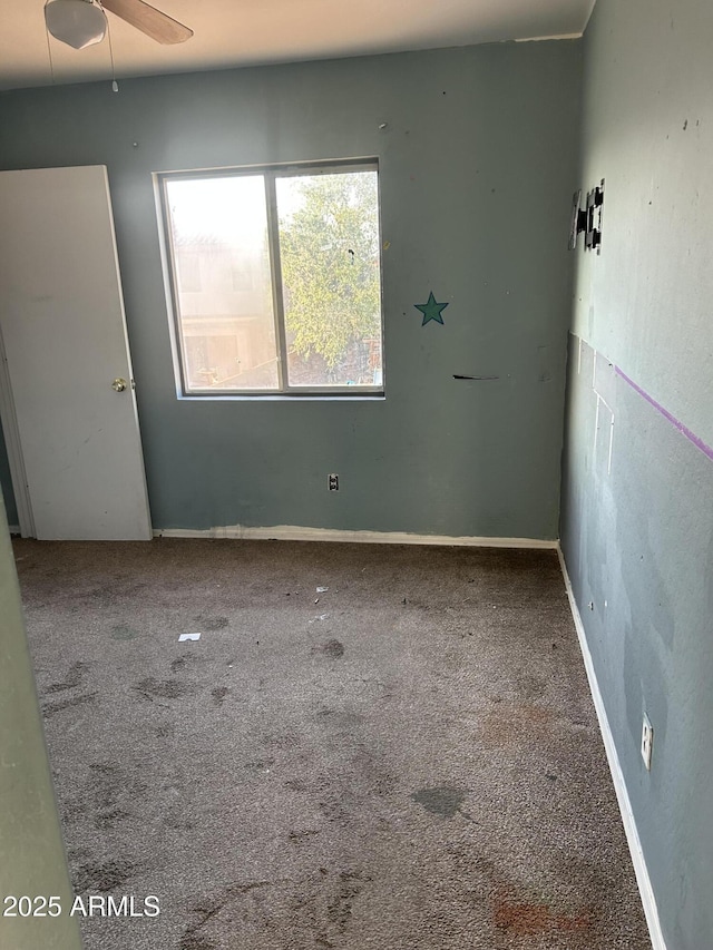 carpeted empty room with a ceiling fan and baseboards