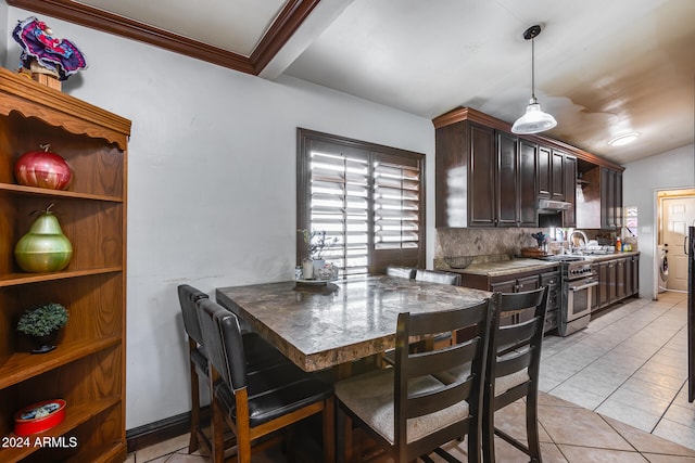 tiled dining space featuring ornamental molding and lofted ceiling