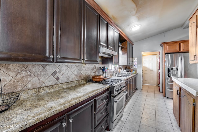 kitchen with stainless steel appliances, lofted ceiling, sink, tasteful backsplash, and light tile patterned floors