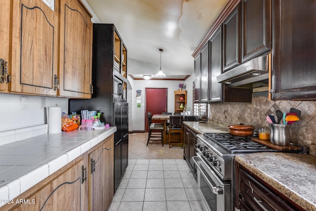 kitchen featuring extractor fan, lofted ceiling, tile counters, stainless steel stove, and pendant lighting