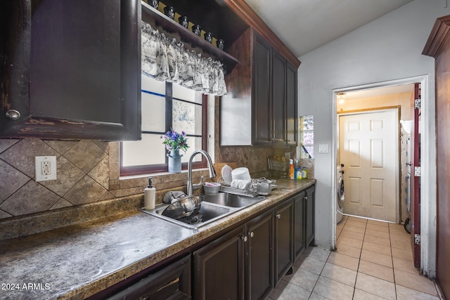 kitchen with dark brown cabinetry, sink, light tile patterned floors, lofted ceiling, and decorative backsplash