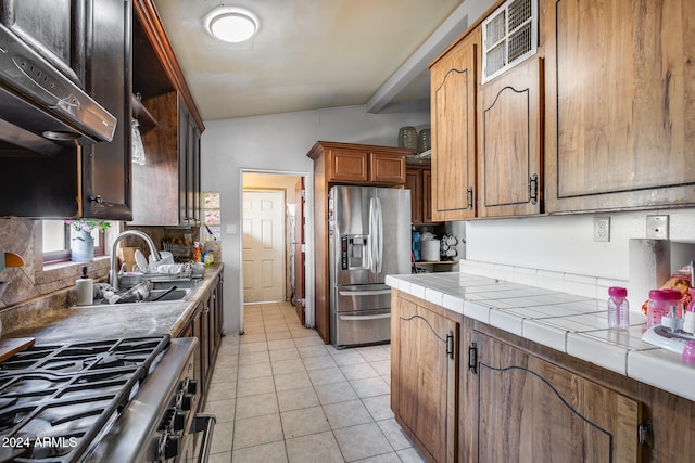 kitchen featuring tile counters, stainless steel appliances, light tile patterned floors, sink, and lofted ceiling with beams