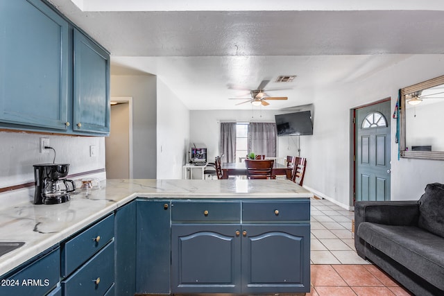 kitchen with blue cabinets, kitchen peninsula, a textured ceiling, and light tile patterned floors