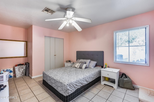 tiled bedroom with ceiling fan and a closet