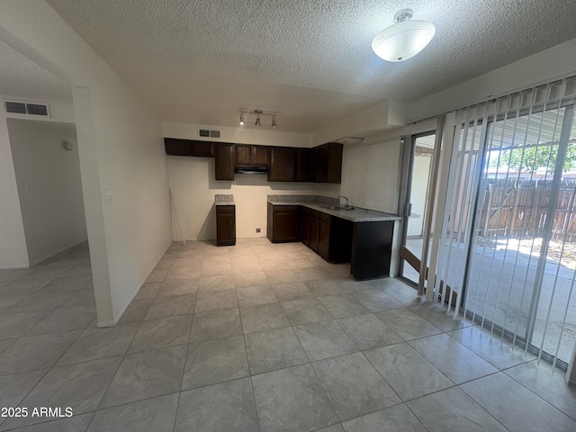 6605 N 46th Ln, Glendale, AZ 85301 - kitchen with a sink, a textured ceiling, dark brown cabinets, under cabinet range hood, and light countertops