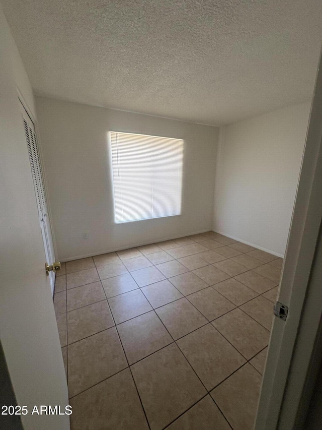 6605 N 46th Ln, Glendale, AZ 85301 - empty room featuring light tile patterned floors, a textured ceiling, and baseboards