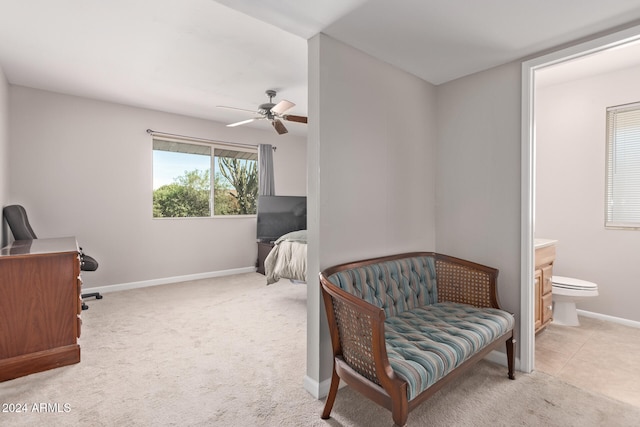 bedroom with connected bathroom, light colored carpet, and ceiling fan