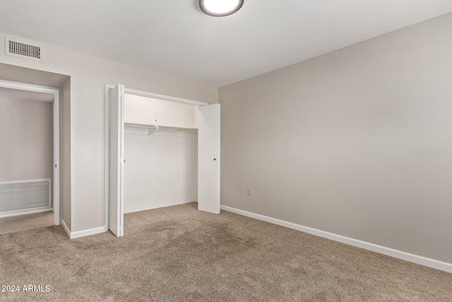 unfurnished bedroom with a closet and light colored carpet