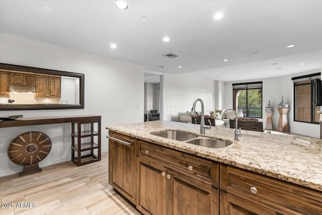 kitchen featuring sink, light hardwood / wood-style floors, and light stone countertops