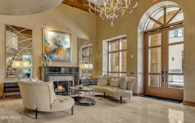 sitting room with an inviting chandelier, a fireplace, french doors, and a high ceiling