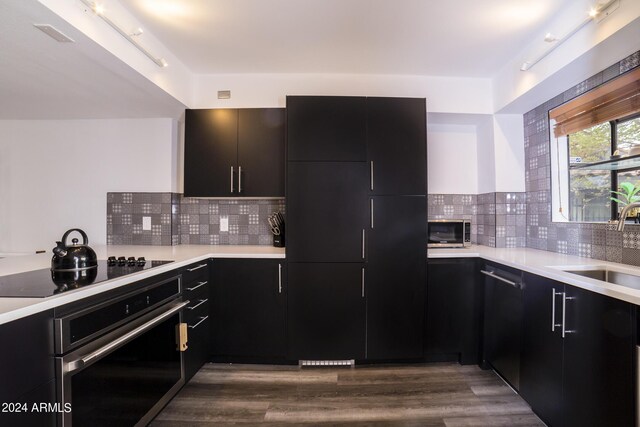 kitchen with decorative backsplash, track lighting, appliances with stainless steel finishes, and light hardwood / wood-style floors