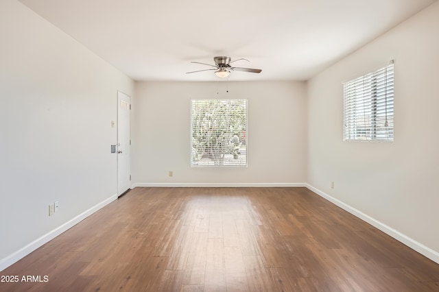 spare room featuring baseboards, wood finished floors, and a ceiling fan