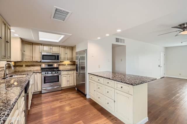 kitchen with a sink, backsplash, stainless steel appliances, and visible vents