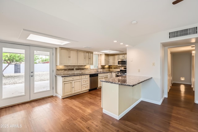 kitchen featuring decorative backsplash, appliances with stainless steel finishes, visible vents, cream cabinetry, and wood finished floors