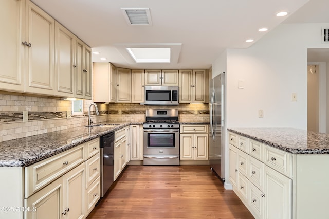 kitchen with cream cabinetry, visible vents, stainless steel appliances, and a sink