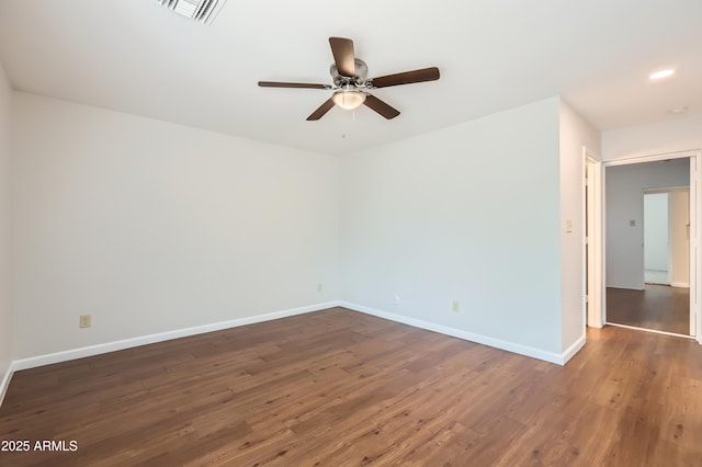 spare room featuring dark wood-type flooring, a ceiling fan, and baseboards