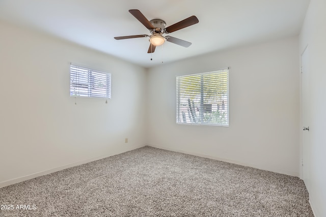 carpeted spare room featuring ceiling fan and plenty of natural light