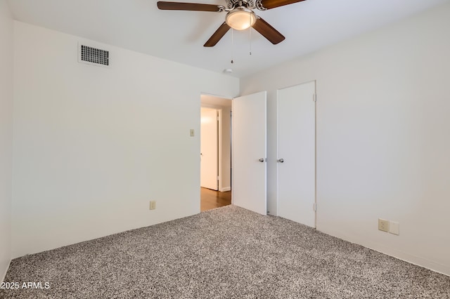 empty room with a ceiling fan, carpet flooring, and visible vents