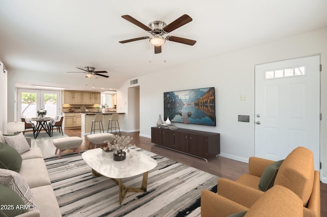 living area featuring wood finished floors, visible vents, ceiling fan, and baseboards