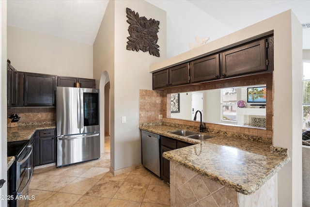 kitchen featuring dark brown cabinetry, sink, stainless steel appliances, and stone countertops