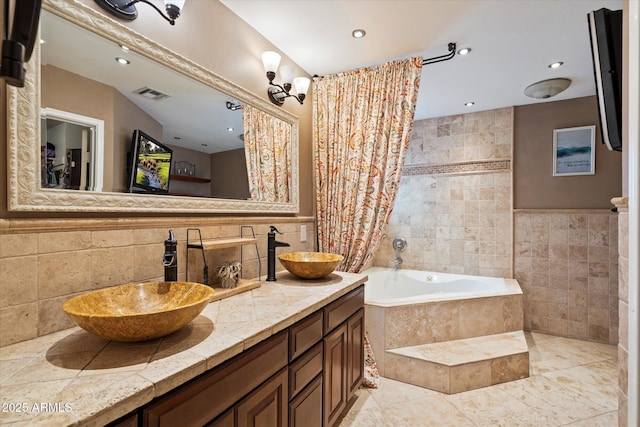 bathroom featuring a relaxing tiled tub, vanity, and tile walls