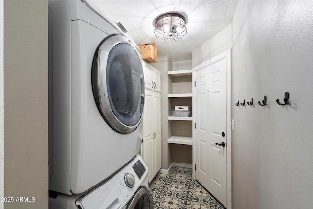 laundry room with stacked washer and dryer, light tile patterned floors, and cabinets