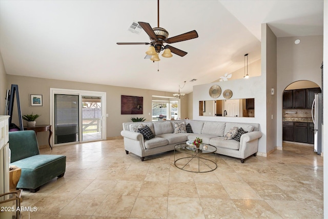 living room with high vaulted ceiling and ceiling fan with notable chandelier