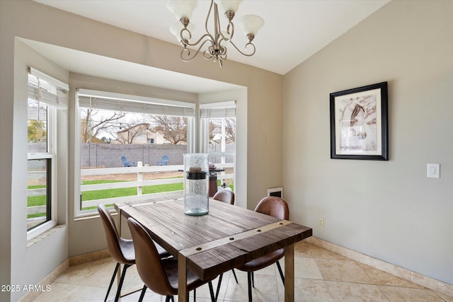 dining space with vaulted ceiling, a healthy amount of sunlight, light tile patterned floors, and a chandelier