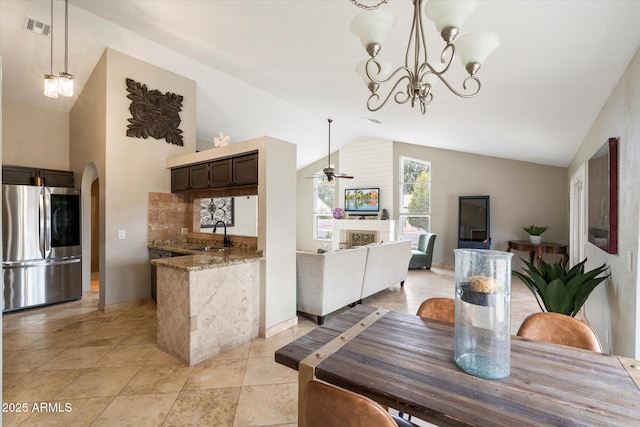 tiled dining area featuring sink, ceiling fan with notable chandelier, and high vaulted ceiling