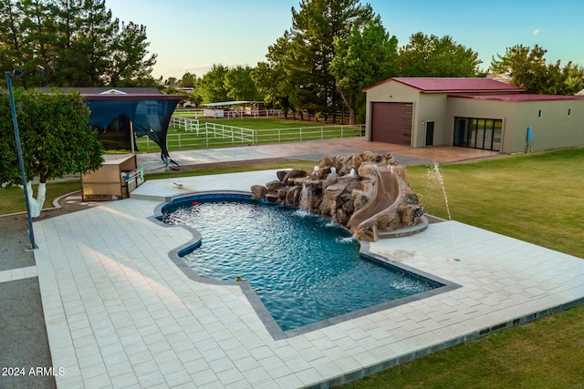 view of swimming pool with pool water feature and a yard