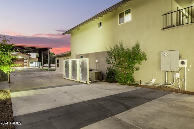 back house at dusk with a carport, cooling unit, and an outdoor structure