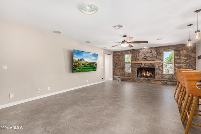 unfurnished living room featuring a fireplace, tile patterned flooring, and ceiling fan