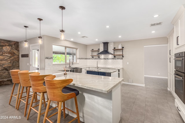 kitchen with a kitchen breakfast bar, white cabinets, decorative backsplash, and wall chimney exhaust hood