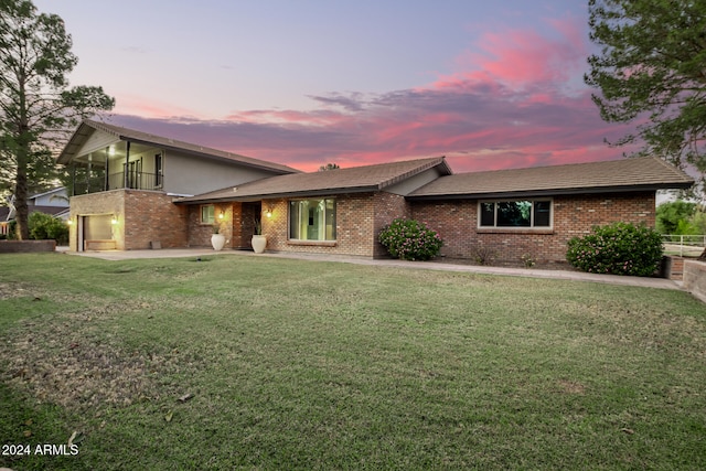 view of front of property with a balcony and a lawn