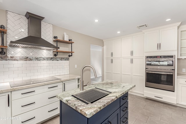 kitchen featuring white cabinets, a kitchen island, wall chimney range hood, and black electric cooktop