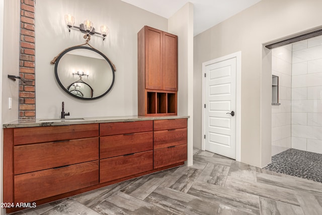 bathroom with a tile shower and vanity