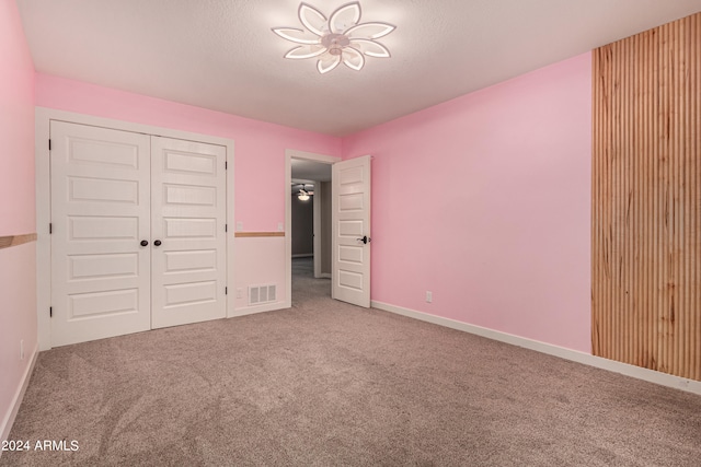 unfurnished bedroom featuring carpet floors, a textured ceiling, and a closet