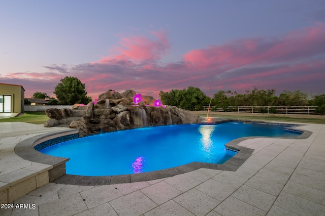 pool at dusk featuring pool water feature