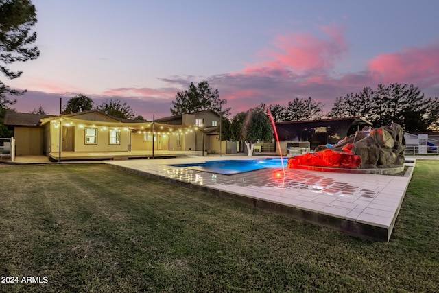 pool at dusk featuring a patio area and a yard