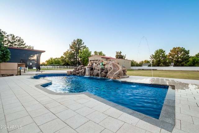 view of swimming pool featuring a lawn, a patio area, pool water feature, and a water slide