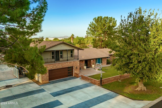 view of front of house featuring a balcony, a garage, and a front lawn