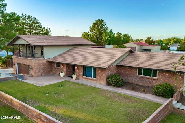 view of front of house featuring a balcony, a front yard, and a garage