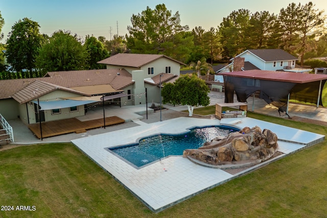 pool at dusk featuring a patio area and a yard