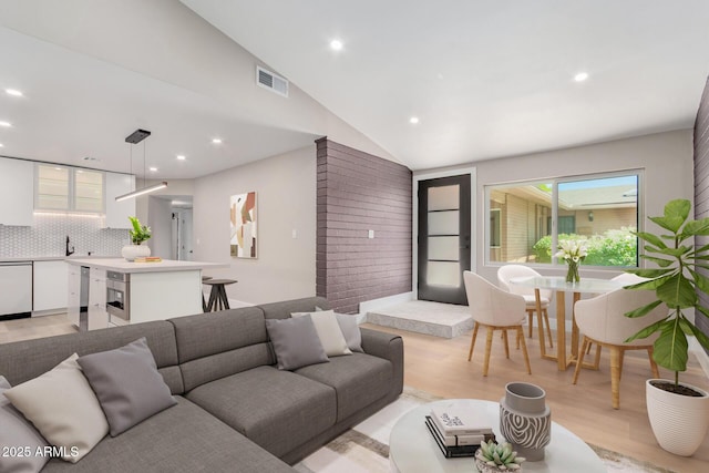 living area with light wood-type flooring, lofted ceiling, and recessed lighting